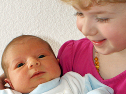 Stolze grosse Schwester mit Baby auf dem Arm